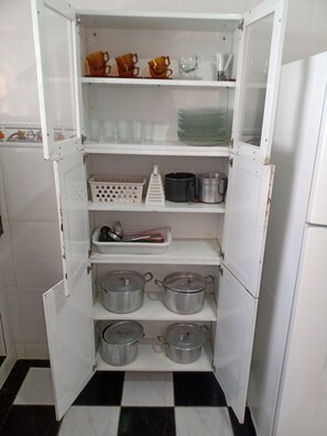 A kitchen with a white refrigerator, a checkered floor, and shelves with pots, pans, and kitchen utensils. - VACATION HOME IN ARARUAMA (Araruama)