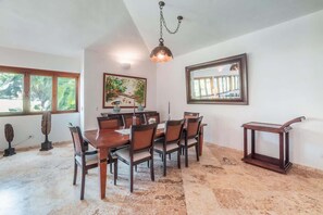 Un comedor con mesa y sillas de madera, una lámpara colgante y un cuadro en la pared.