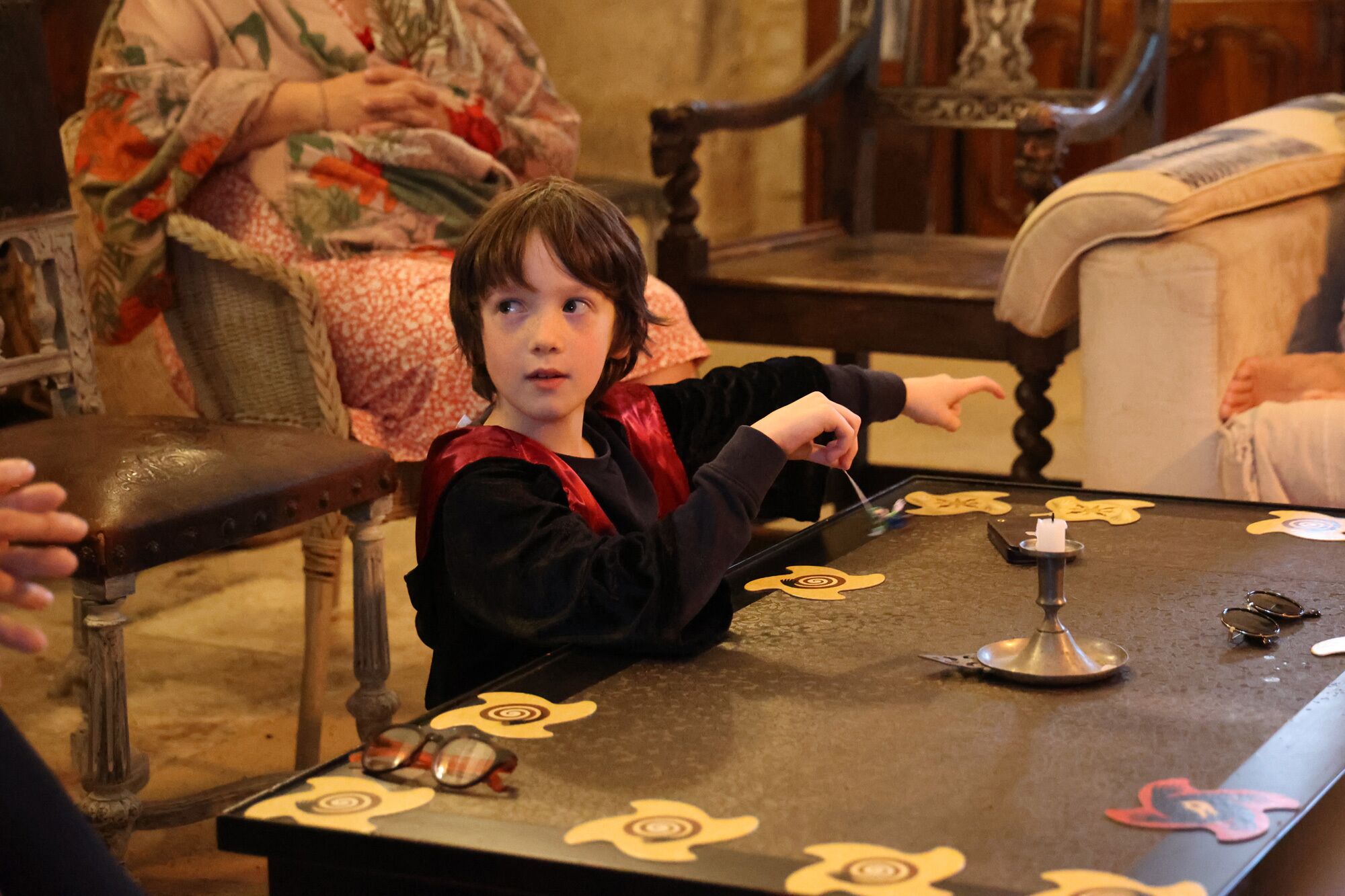 A child playing with a toy at a table with a decorative pattern.