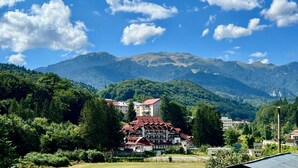 Ein Hotel mit rotem Dach, umgeben von üppiger Vegetation und Bergen im Hintergrund.