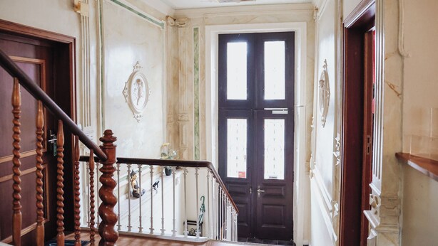 A grand staircase with ornate woodwork and a dark wooden door at the top. - Hotel Villa Kisseleff (Bad Homburg v.d. Hoehe)