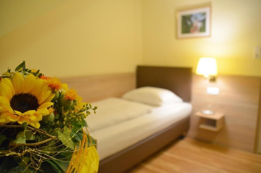 A hotel room with a bed, a nightstand with a lamp, and a framed picture on the wall.