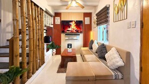 Ein Wohnzimmer mit Fernseher, Sofa und Deckenventilator.