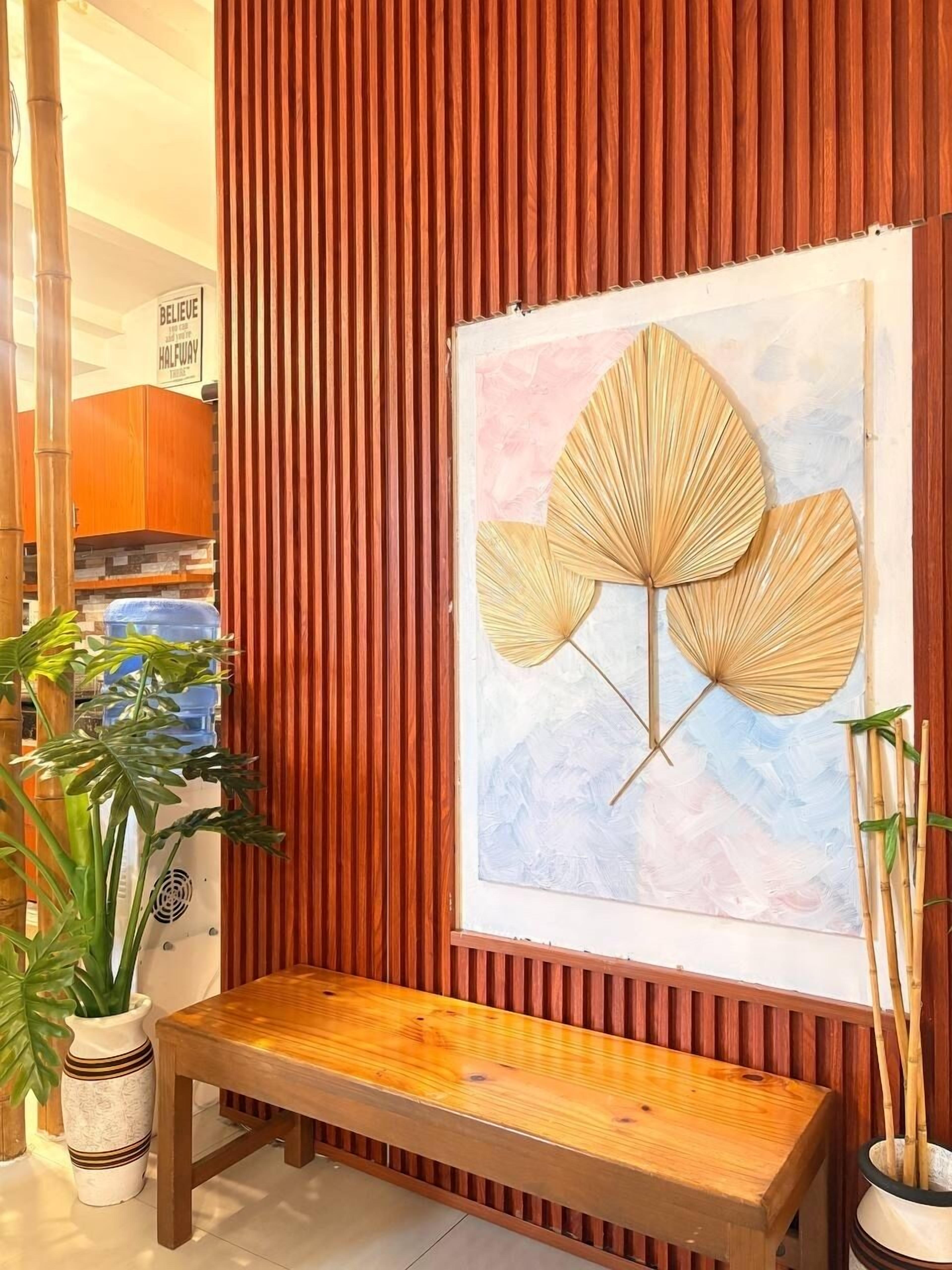 Ein Zimmer mit einer hölzernen Sitzbank, einem Wandventilator und einem gerahmten Kunstwerk.
