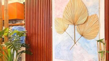 Ein Zimmer mit einer hölzernen Sitzbank, einem Wandventilator und einem gerahmten Kunstwerk.