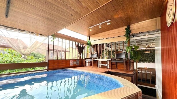 Ein Pool mit Holzterrasse und Whirlbereich.
