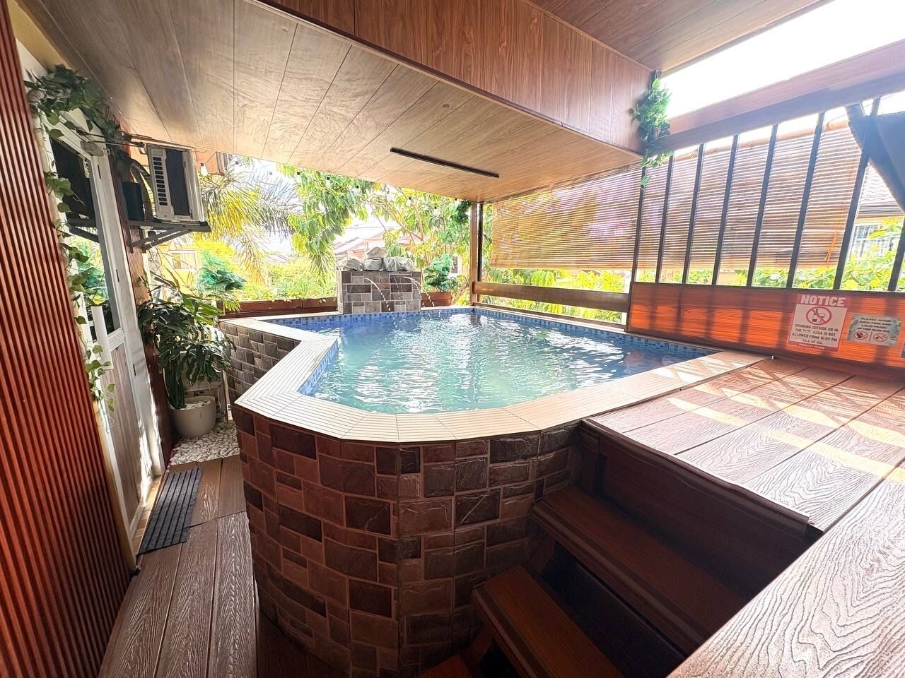 Un bain à remous entouré de briques, avec une terrasse en bois et une vue sur la verdure.