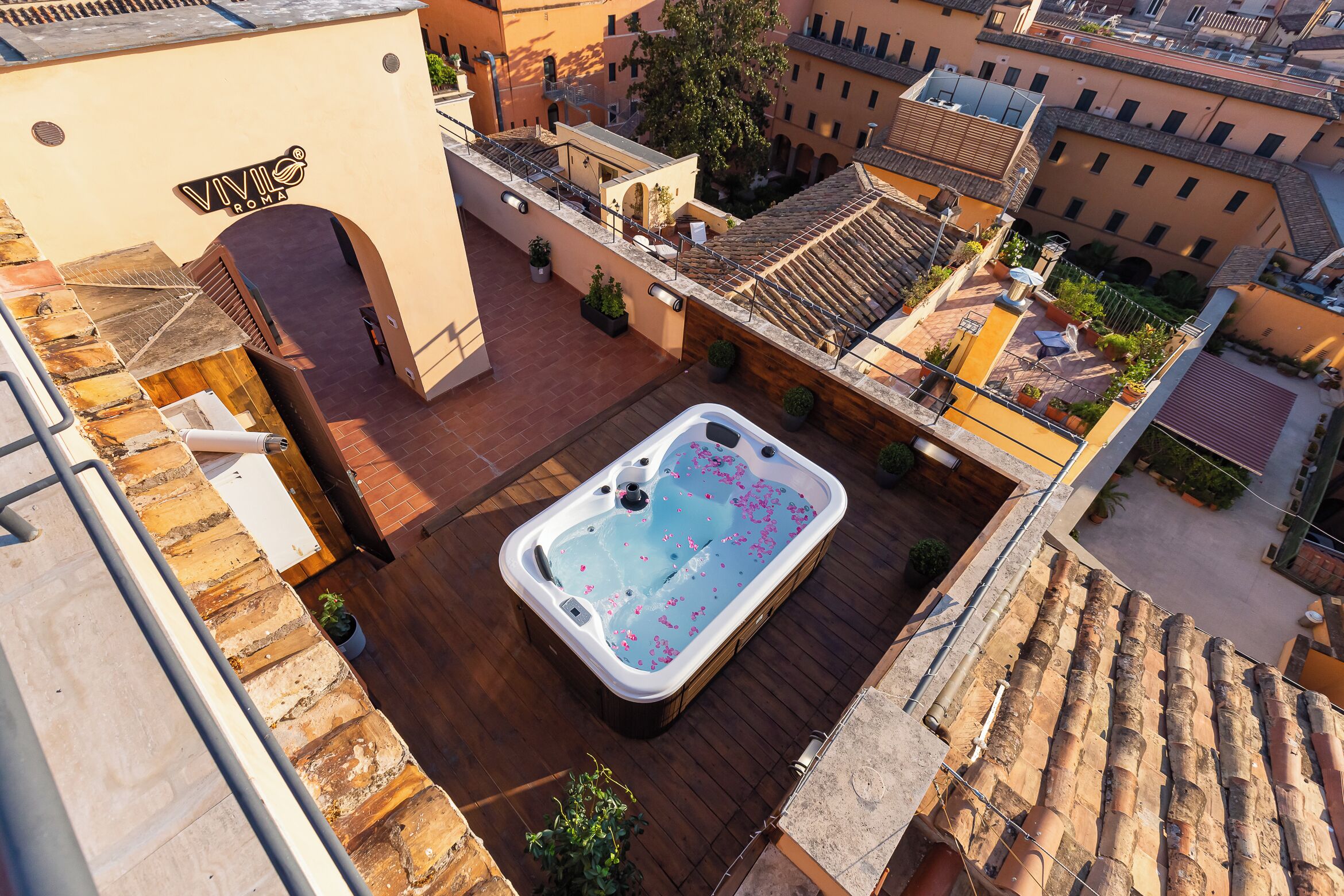 Eine Dachterrasse mit Whirlpool, umgeben von Topfpflanzen und einer Steinmauer.