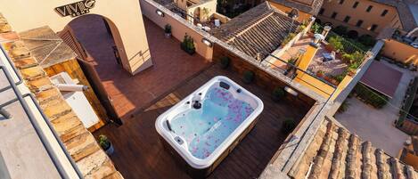 Eine Dachterrasse mit Whirlpool, umgeben von Topfpflanzen und einer Steinmauer.