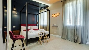 A modern bedroom with a four-poster bed, a red chair, a wooden stool, and a neon sign. - VIVILO COLLECTION - Vivilo Roma Trevi (Terrace+Jacuzzi) Close to Trevi Fountain (Roma)