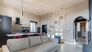 A modern kitchen with a built-in stove, a dining area with a sofa, and pendant lighting. - VIVILO COLLECTION - Vivilo Roma Trevi (Terrace+Jacuzzi) Close to Trevi Fountain (Roma)
