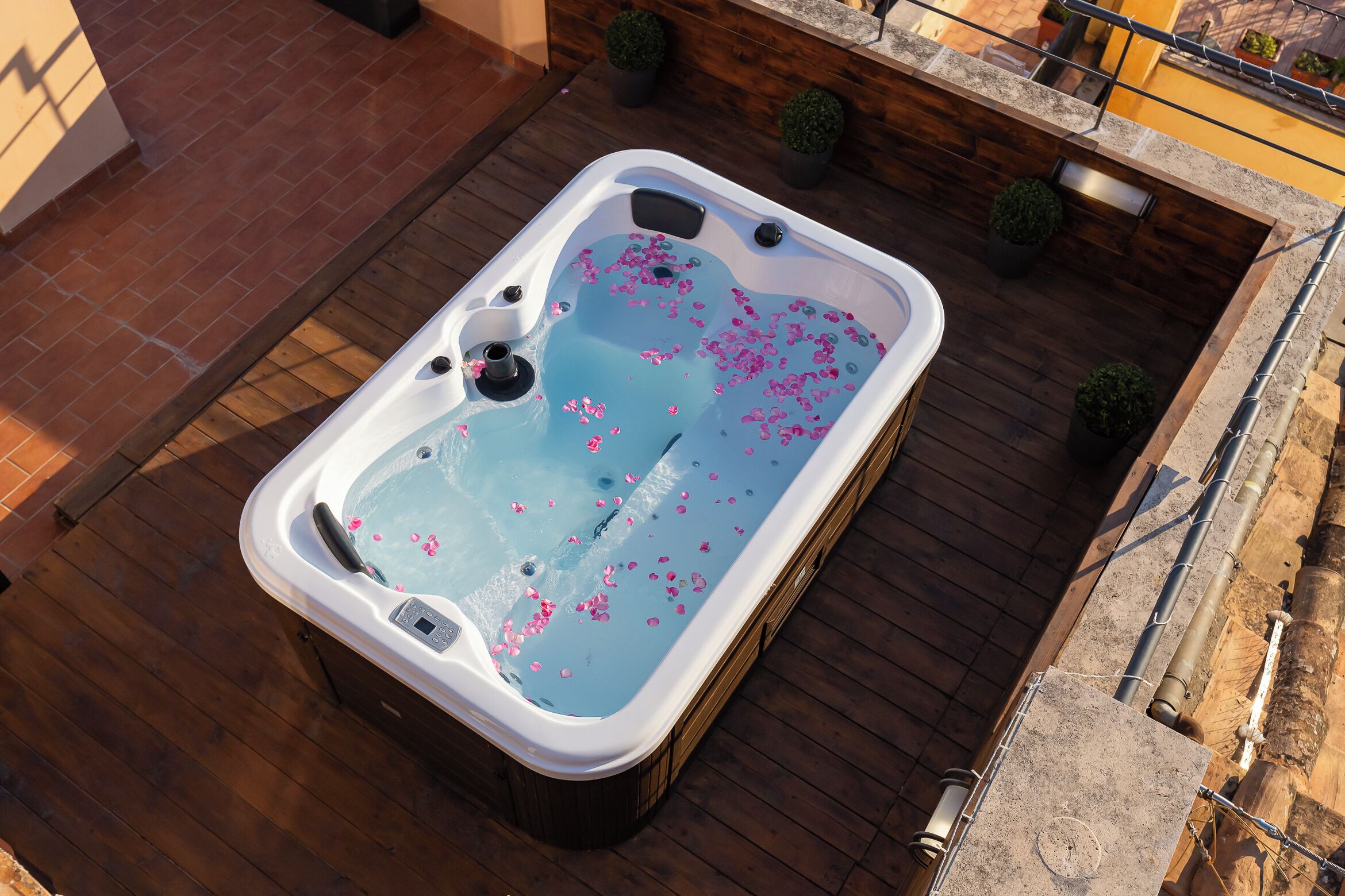 A hot tub with rose petals on a wooden deck.