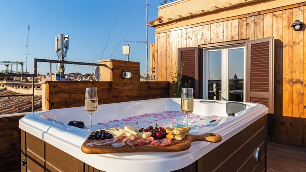 A wooden deck with a hot tub, wooden deck chairs, and a wooden table with a variety of cheeses, meats, and fruits. - VIVILO COLLECTION - Vivilo Roma Trevi (Terrace+Jacuzzi) Close to Trevi Fountain (Roma)