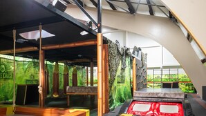 An indoor jungle-themed play area with climbing walls, a trampoline, and wooden benches. - Couple Stay at Hambachtal Holiday Park (Oberhambach)