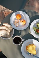 Ein Tisch mit Brot, Orangenscheiben, Avocado und einer Tasse Kaffee, dazu eine Scheibe Toast.