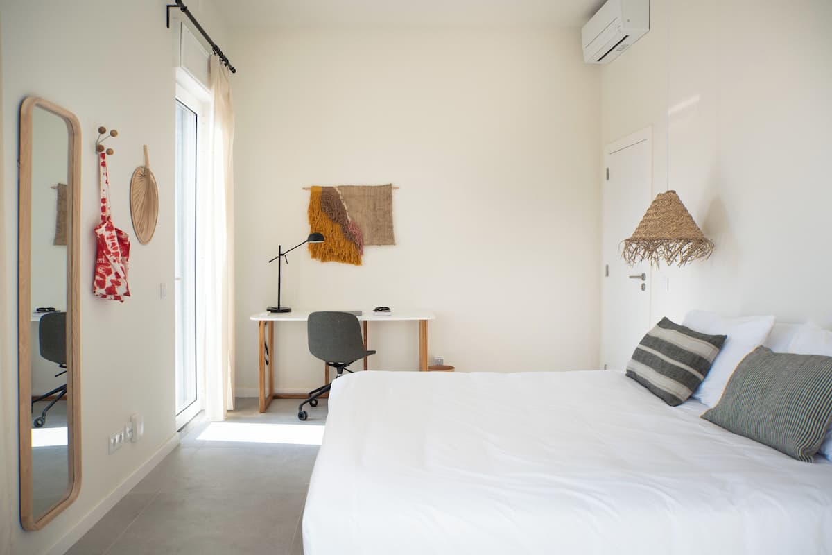 A bedroom with a large bed, a desk, and a chair.