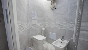 A bathroom with a toilet, bidet, and a sink.