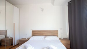 A modern hotel room with a large bed, wooden headboard, and a mirror on one wall.