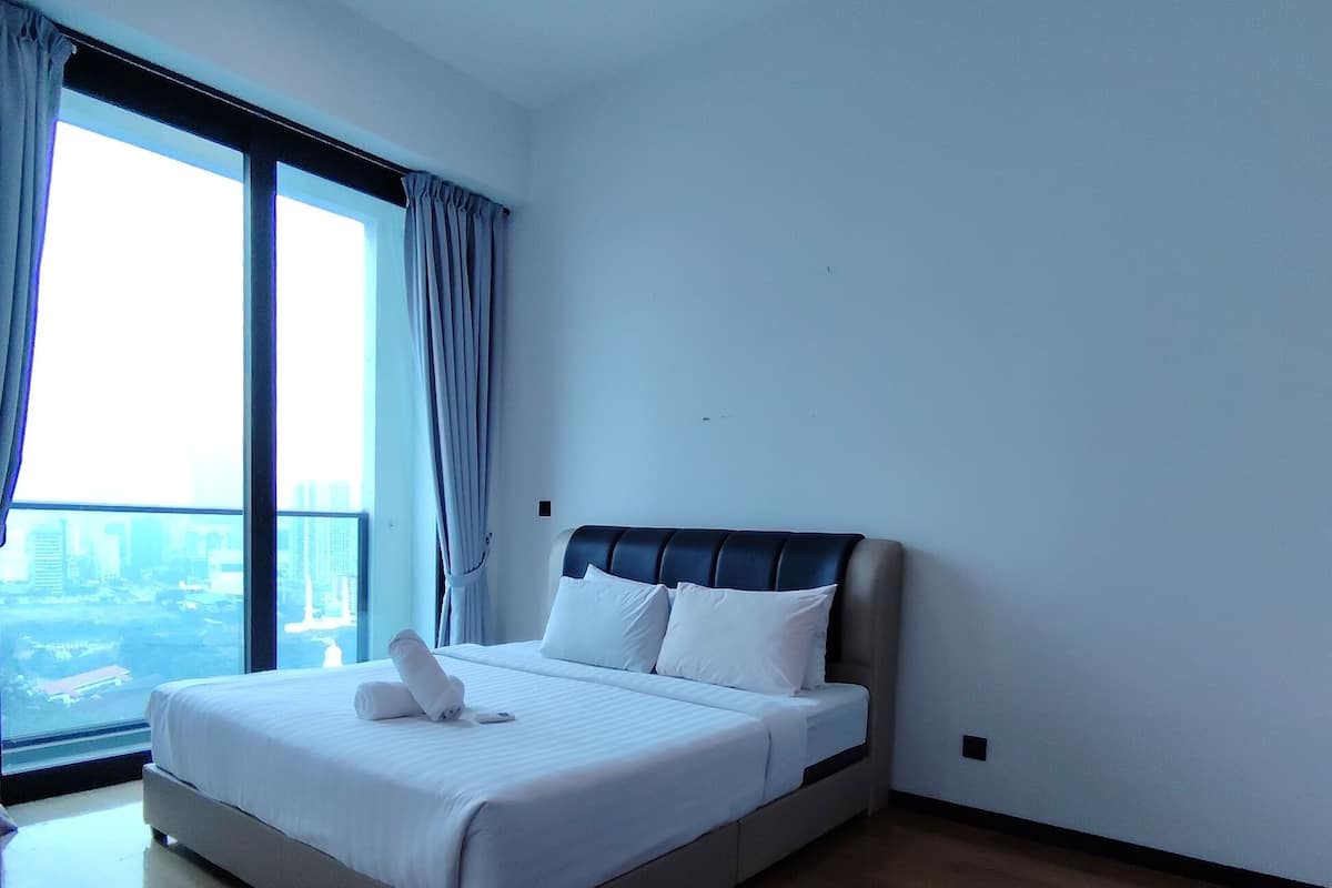 Een moderne hotelkamer met een groot bed, een plafondventilator en uitzicht op de stad door het raam.