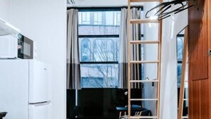 A modern kitchen with white cabinets, a wooden ceiling, and a view through a window. - Cozy Suites (Tallinn)