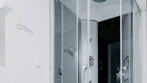 A modern bathroom with a glass-enclosed shower, a white sink, and a tiled floor. - Cozy Suites (Tallinn)