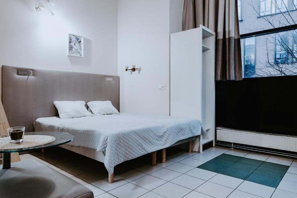 A bedroom with a bed, bedside table, and a window with curtains.