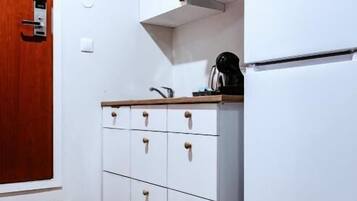 Una cocina con armarios blancos, una puerta de madera y un refrigerador blanco.