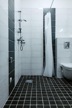 Un baño con ducha, inodoro y piso de baldosas.