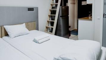 Une chambre d’hôtel équipée d’un lit, d’une armoire, d’un réfrigérateur et d’une échelle en bois.