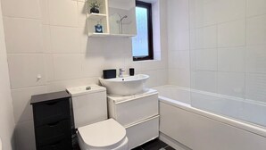 A modern bathroom with a toilet, sink, and bathtub.