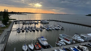 A marina with boats docked at a pier, surrounded by calm water and a cloudy sky. - Hausboot Paula mit Reisekajak in Ribnitz-damgarten (Ribnitz-Damgarten)