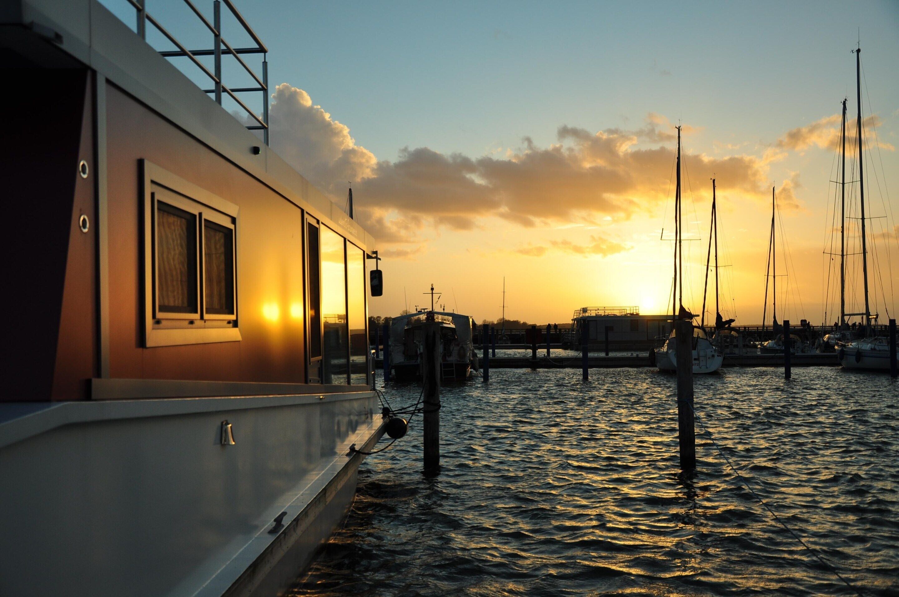 Ein Boot liegt in einer Marina vor einem Sonnenuntergang.