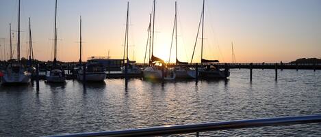 Un port de plaisance où sont amarrés de nombreux voiliers, au coucher du soleil.