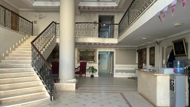En rymlig entréhall med en imponerande trappa, en receptionsdisk och en balkong på andra våningen.