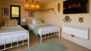 Ein Schlafzimmer mit zwei Betten, einem Fernseher und einem Wandheizgerät.