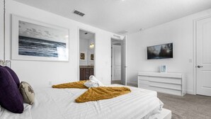 Une chambre moderne dotée d’un grand lit, d’un téléviseur à écran plat et d’un dressing.