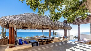 A beachside patio with a thatched roof, lounge chairs, and a pool table. - Casa Dos Hermanas by Wynwood House (Cabo San Lucas)