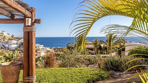 A coastal view with a wooden pergola, lush greenery, and a clear blue sky. - Casa Dos Hermanas by Wynwood House (Cabo San Lucas)