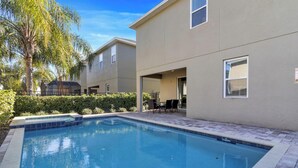 A swimming pool area with a patio, a covered seating area, and a building with a beige exterior. - 25% Off 8BR Villa! Pool/Spa.  Game & Movie Rooms (Davenport)
