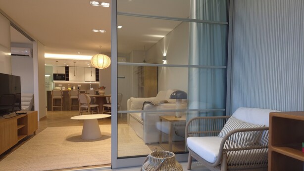 A modern living room with a sofa, a wicker chair, a TV, and a dining area with chairs and a table. - Shell Living -Marina (FUNCHAL)