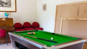 A pool table with balls, a globe, and red chairs in a room with a wooden floor and a white wall. - Solo Country Getaway in Kent (Ashford)