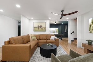 A modern living room with a sectional sofa, a round coffee table, and a ceiling fan. - The Clubhouse Escape - sleeps 10! Movie theater, hot tub, pool, billiards! (Scottsdale)
