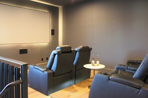 A home theater room with reclining chairs, a small table with bottles, and a large screen. - The Clubhouse Escape - sleeps 10! Movie theater, hot tub, pool, billiards! (Scottsdale)