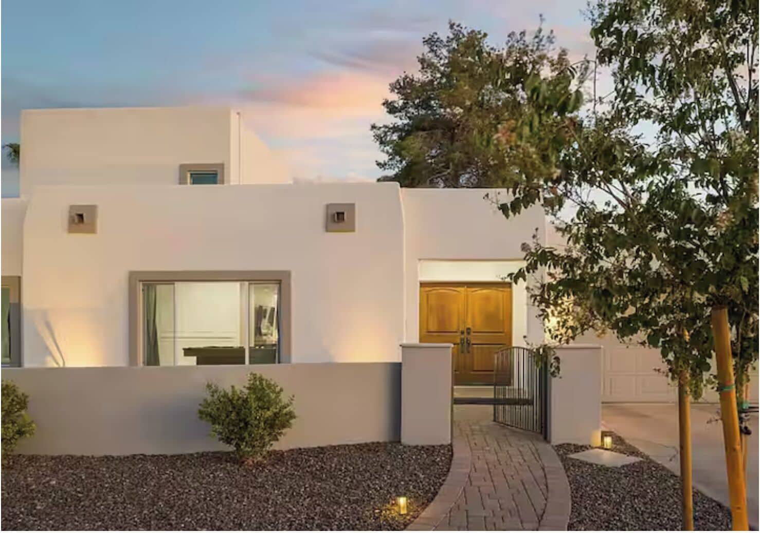 A modern building with a flat facade, a central entrance, and a small garden area with gravel and a pathway.