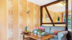 Una habitación con una mesa de madera, un sofá y una pared con papel tapiz estampado.