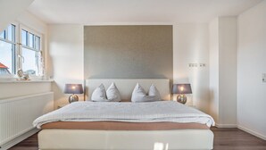 Ein Schlafzimmer mit einem großen Bett, zwei Nachttischlampen, einem Fenster mit Blick und einer Heizung.