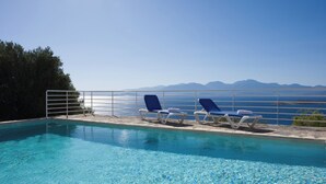 Ein klares, blaues Schwimmbecken mit Liegestühlen und Blick auf Berge.