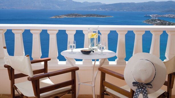 Ein Balkon mit einem Tisch für zwei Personen, der einen malerischen Blick auf das Meer und vorgelagerte Inseln bietet.