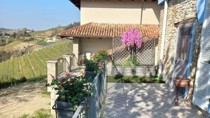 A villa with a tiled roof, a stone facade, and a balcony with potted plants and flowers. - CASA MILU' (Piemonte)