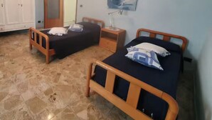 A bedroom with two wooden beds, a wardrobe, a mirror, and a ceiling light fixture. - CASA MILU' (Piemonte)